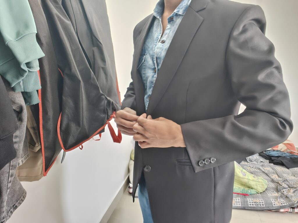 Person adjusting a button on a garment at a clothing rack