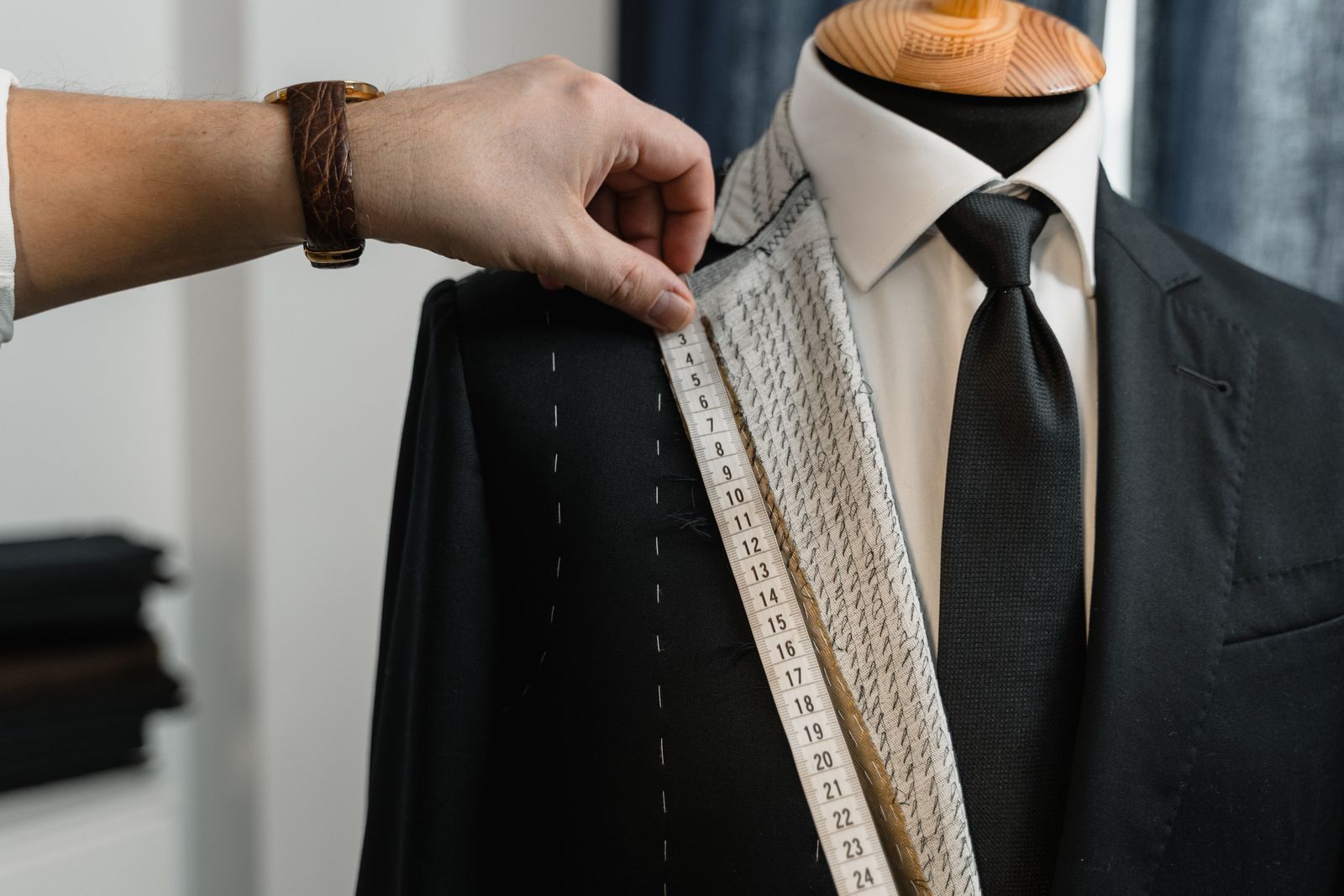 Tailor measuring the lapel and shoulder construction of a tailored jacket