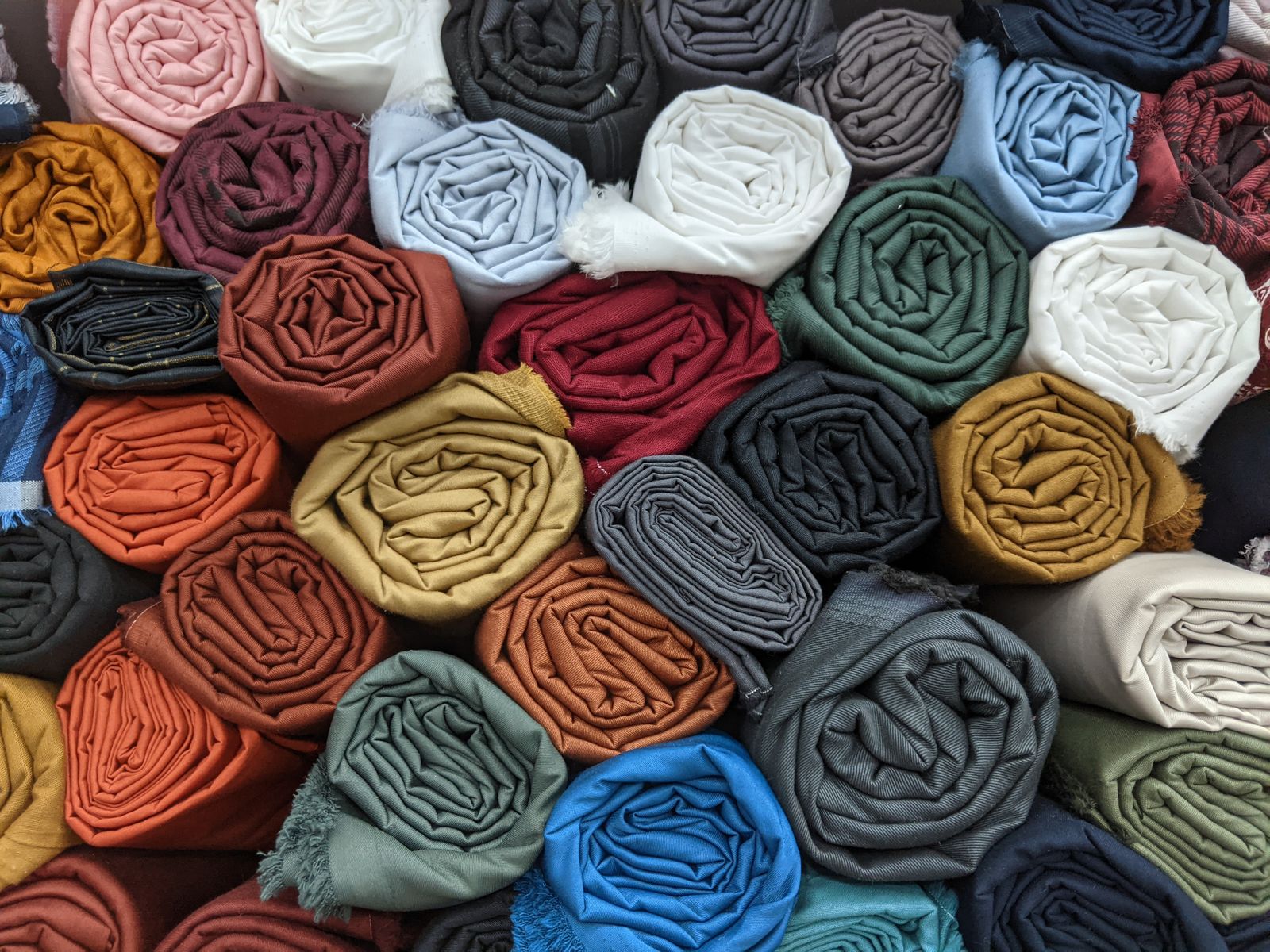 Rolls of woven shirting fabrics in assorted colors for material review