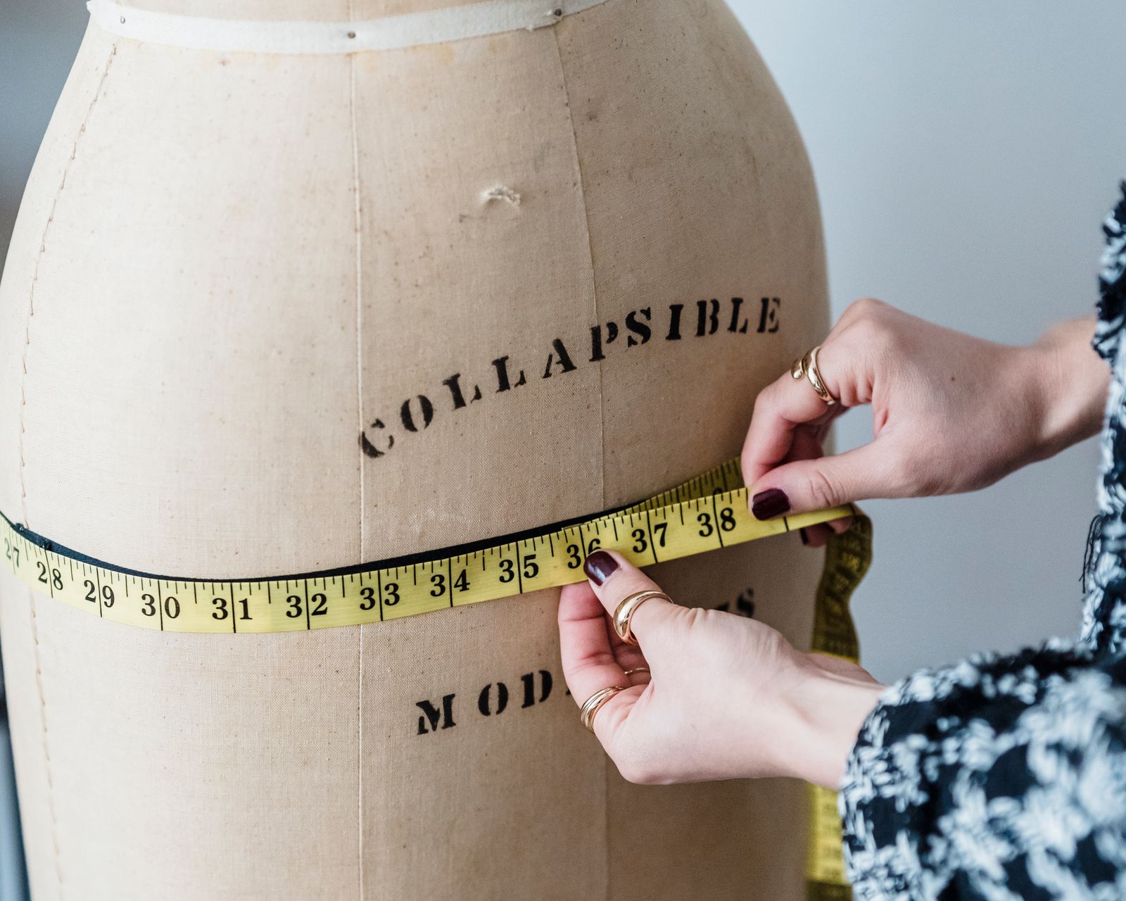 Seamstress measuring a dress form with a tape to review skirt fit and drape