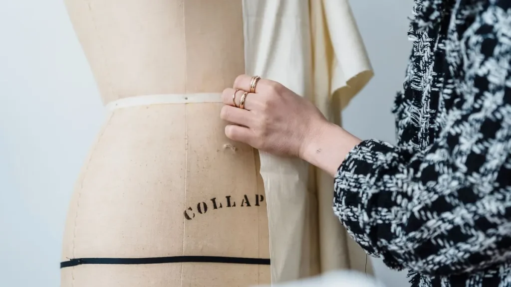 Designer reviewing fabric drape on a garment dress form