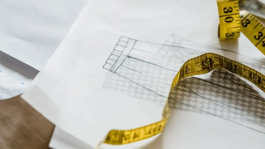 Measuring tape placed over a garment sketch in a design workshop