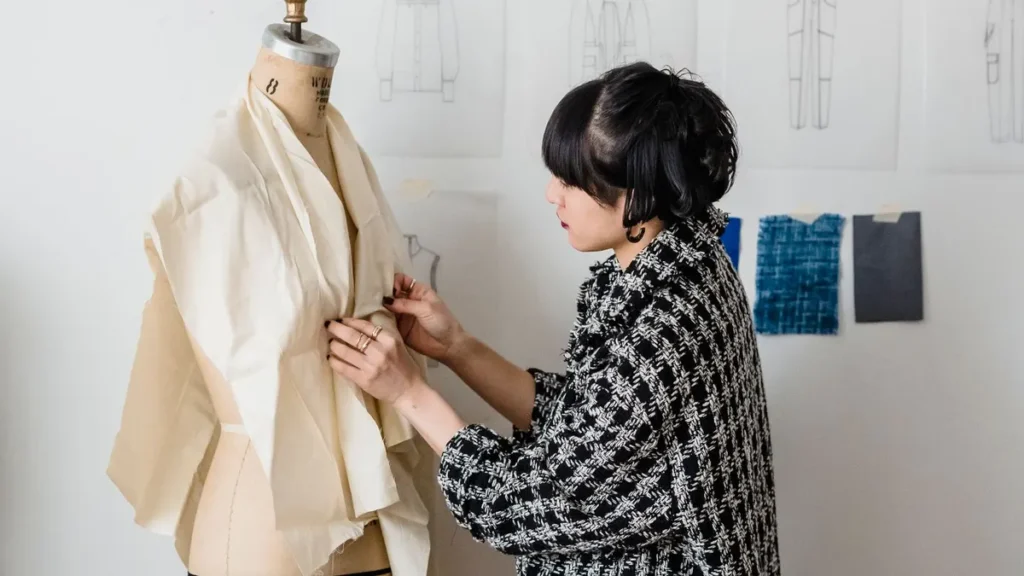 Designer measuring fabric on a dress form during sample development