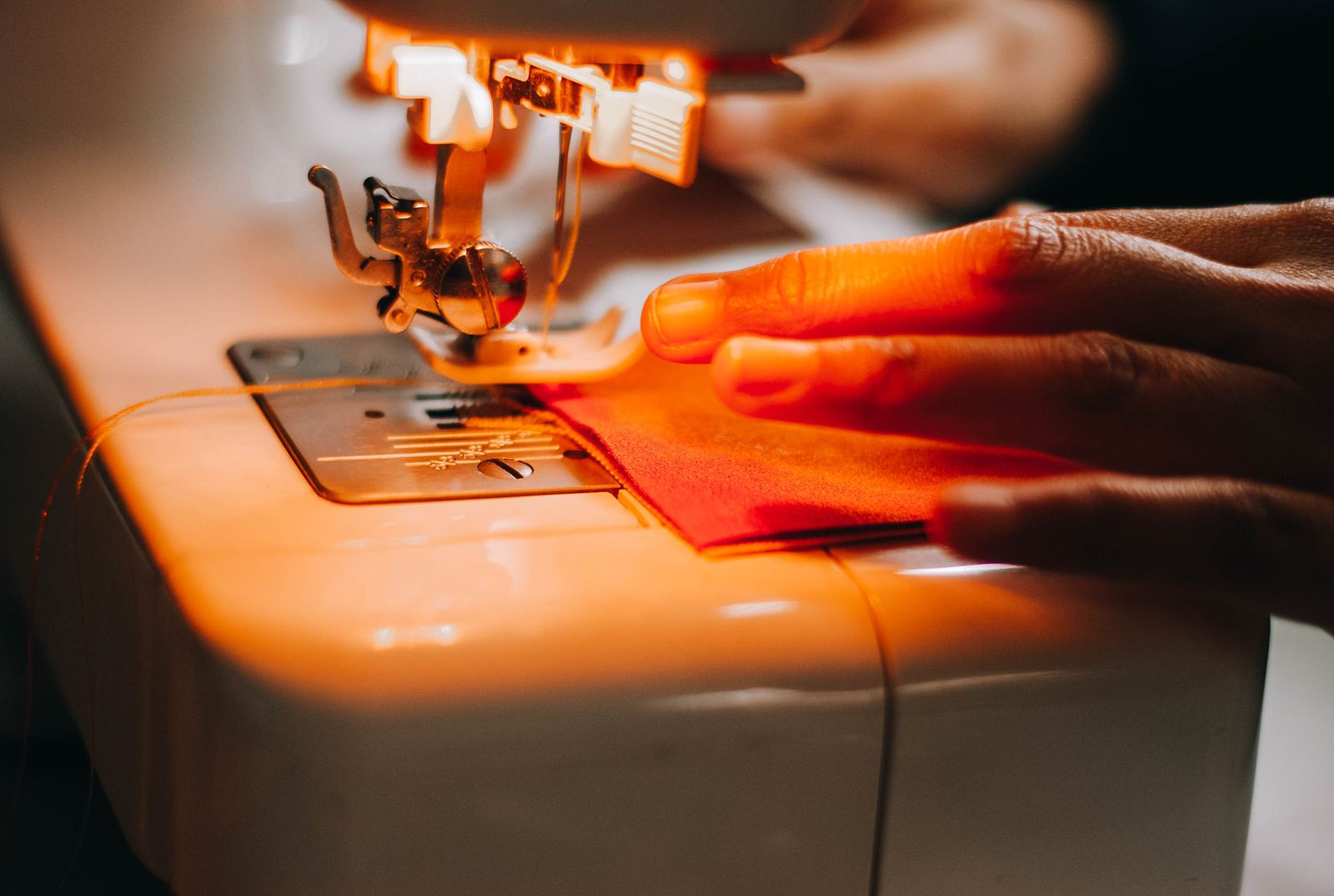 Operator guiding fabric through an industrial sewing machine during garment assembly