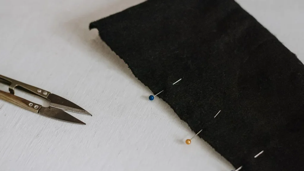 Black fabric and sewing pins prepared for custom garment construction