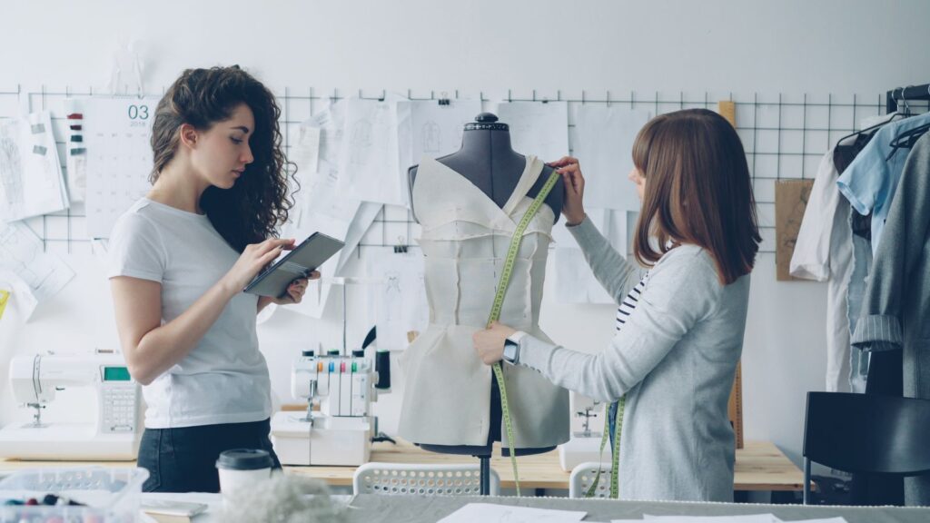 Two fashion designers reviewing a garment on a mannequin in a bright studio