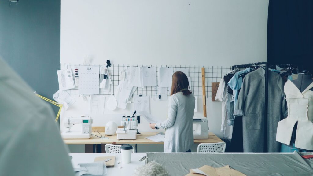 Fashion designer reviewing pattern sheets pinned on a studio wall
