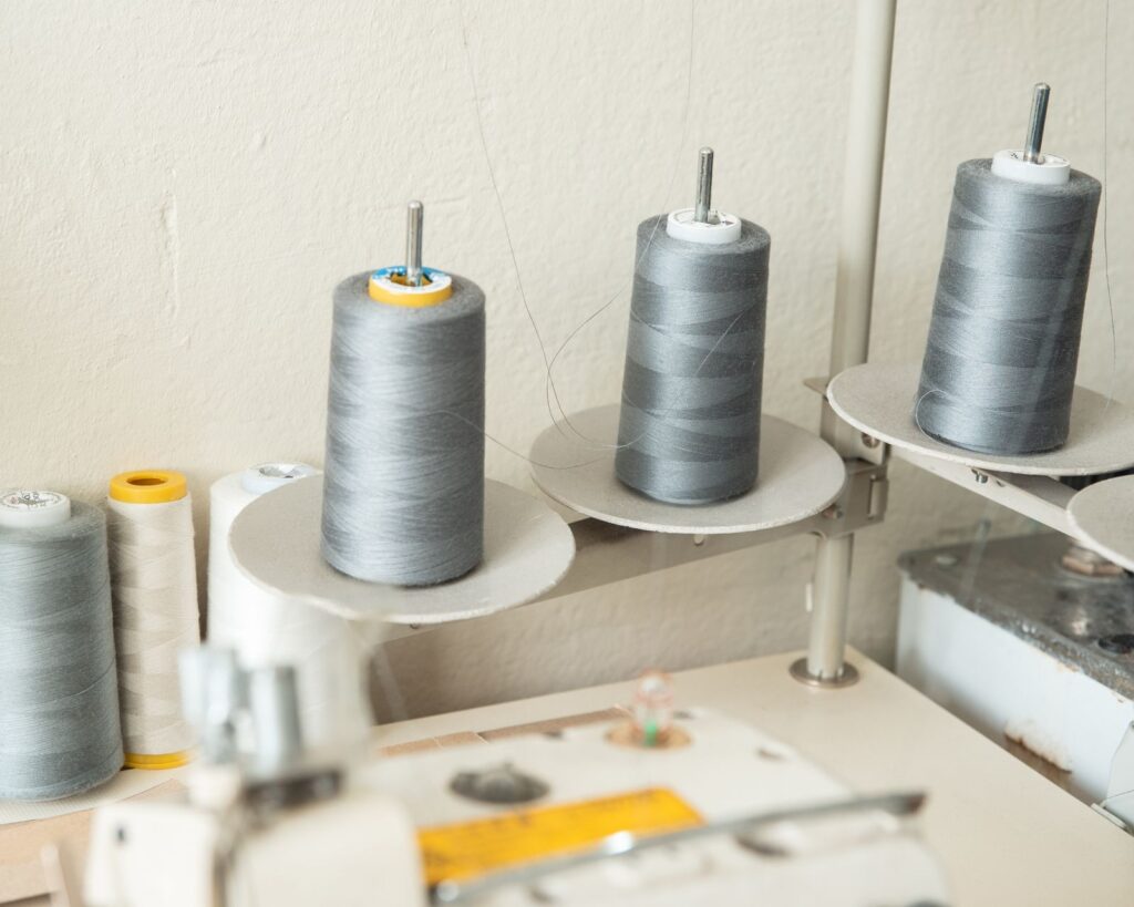 Grey thread spools on an industrial Juki sewing machine