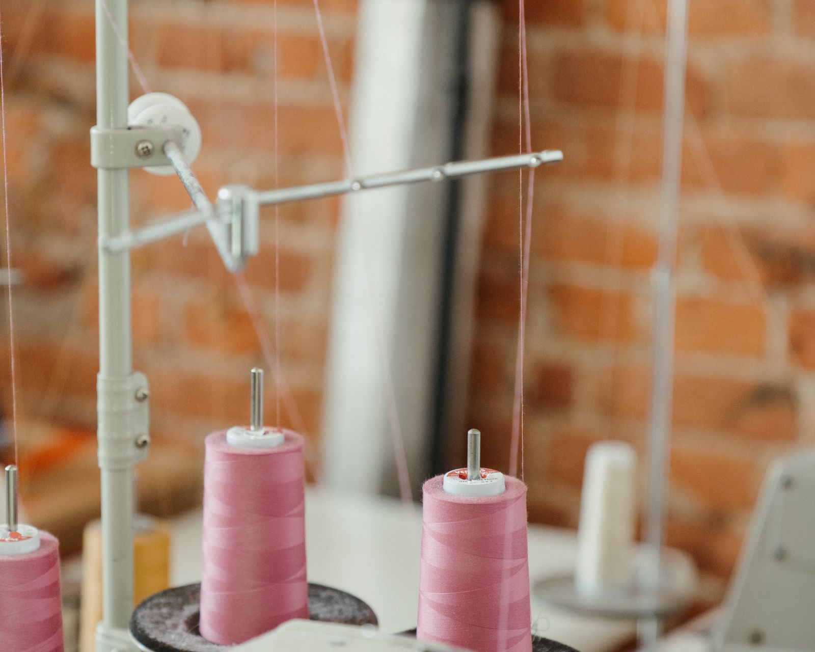 Pink thread spools on an industrial sewing machine
