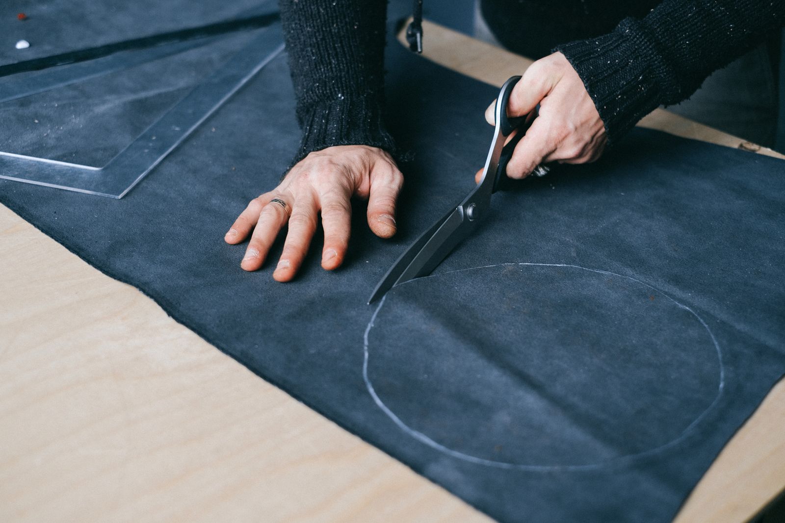 Tailor cutting dark fabric along a chalk marker line