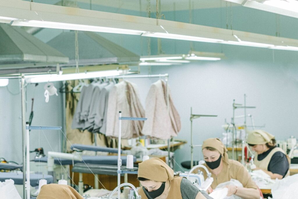 Chinese sewing operators in masks assembling woven garments in a bright workshop