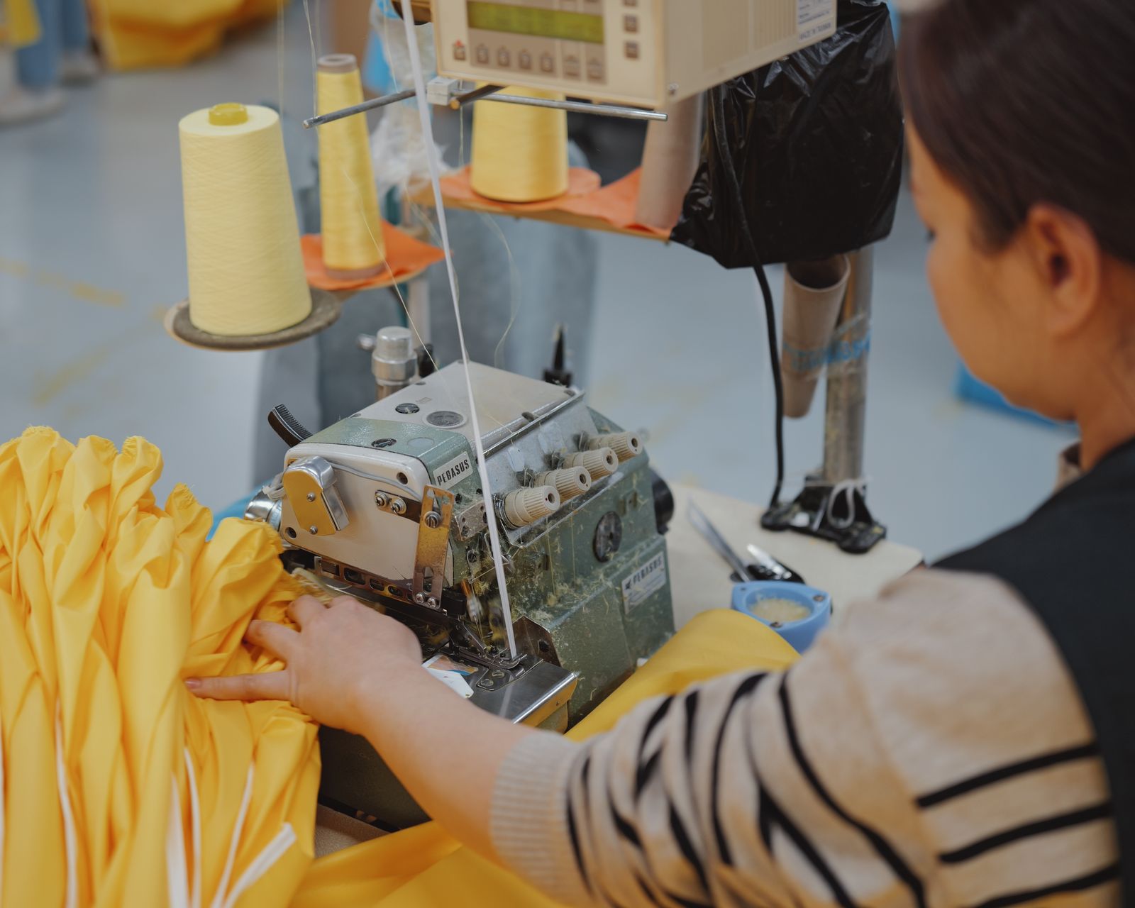 Chinese operator overlocking yellow woven fabric on an industrial machine