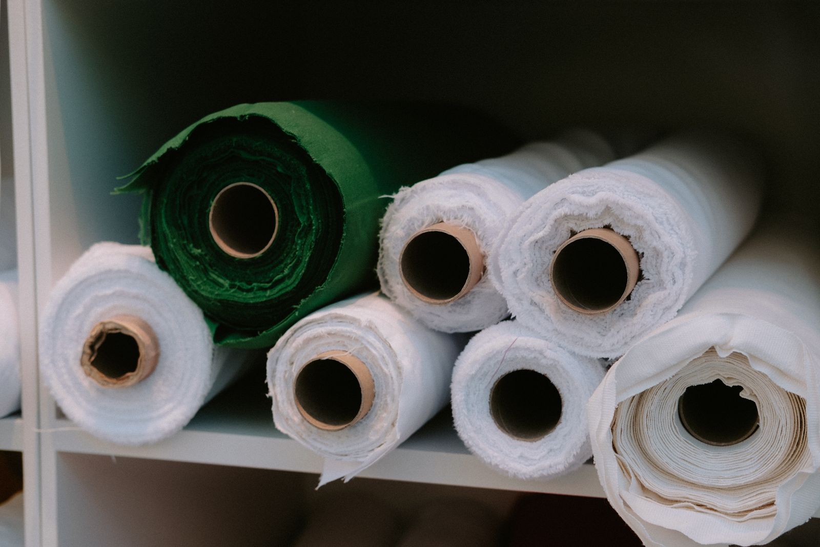 Rolls of woven fabric stored on a studio shelf for material review