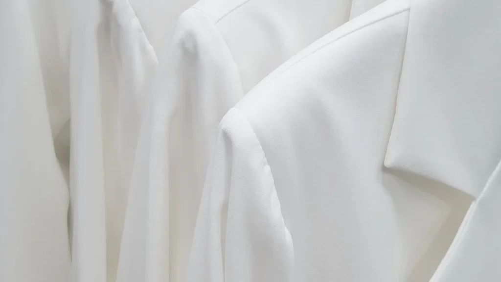 Row of white tailored blazers hanging on a garment rack
